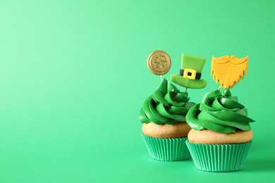 Photo of Decorated cupcakes on green background, space for text. St. Patrick's Day celebration