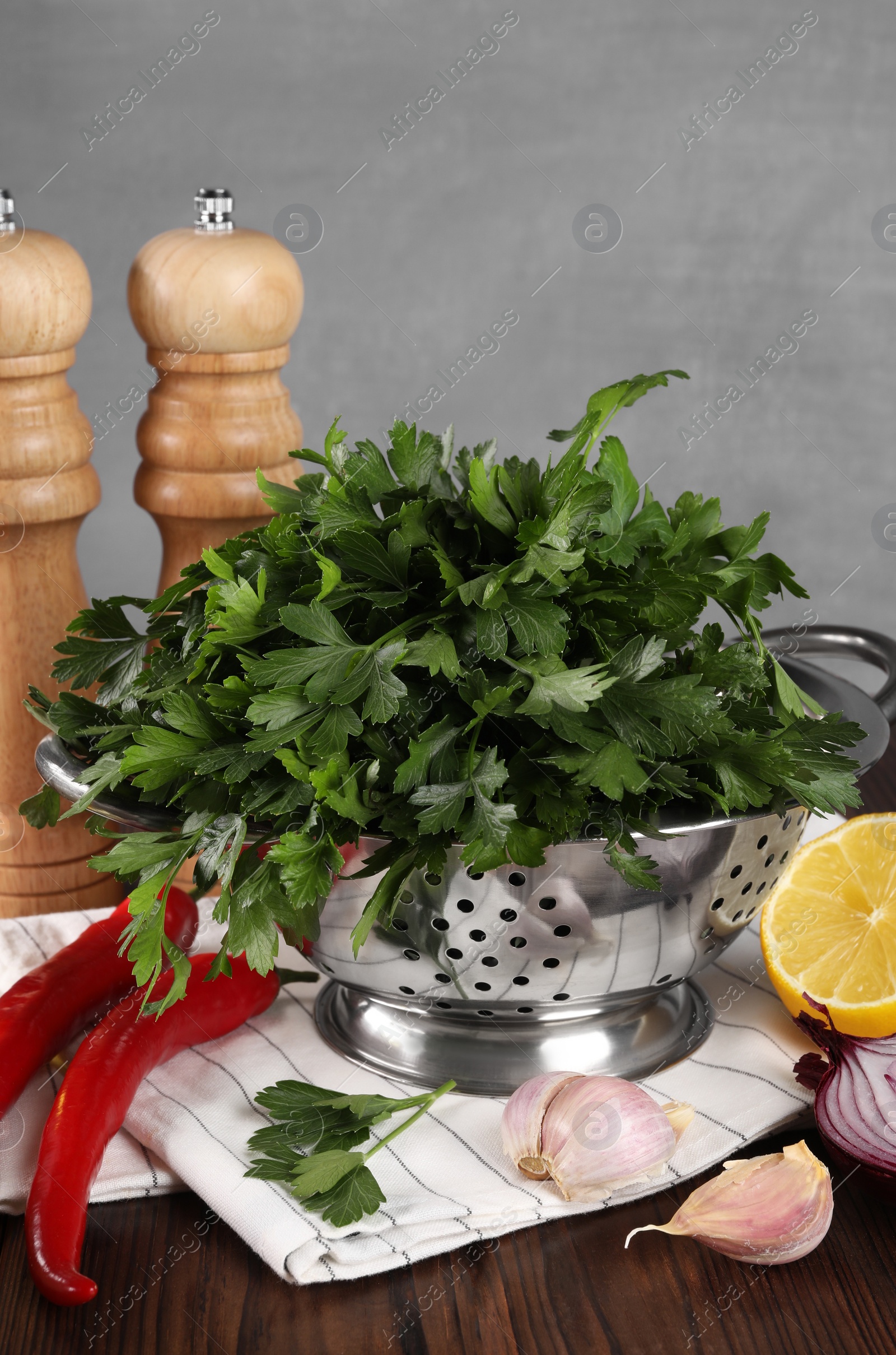 Photo of Colander with fresh parsley, spices and other products on wooden table