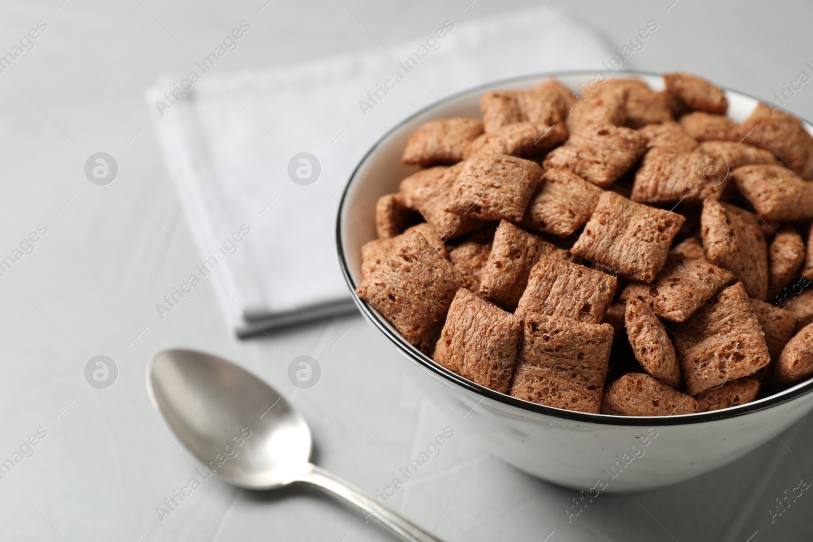 Photo of Sweet crispy corn pads in bowl and spoon on light table, closeup