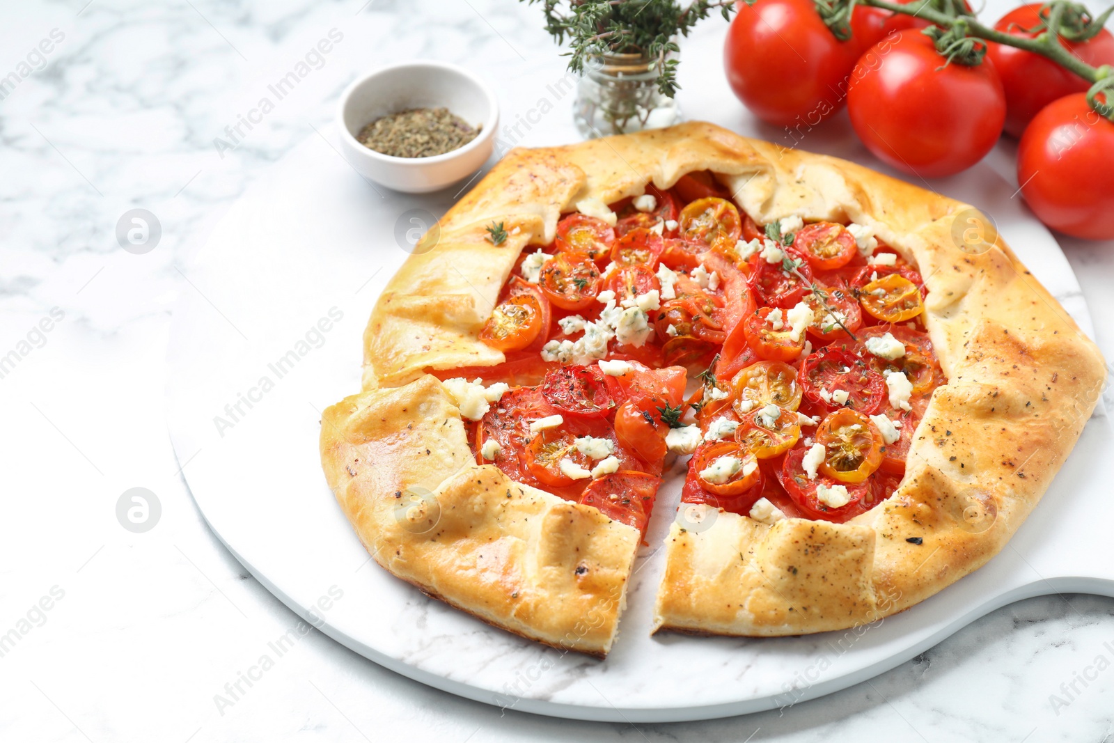 Photo of Tasty galette with tomato, thyme and cheese (Caprese galette) on white marble table, closeup