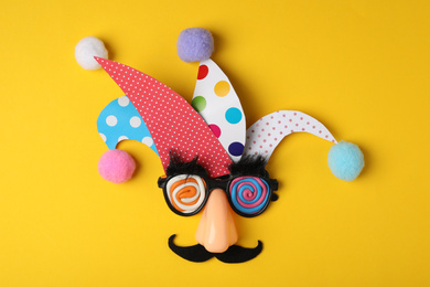 Photo of Funny face made of party items on yellow background, flat lay. April Fool's Day
