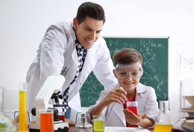 Photo of Teacher with pupil making experiment at table in chemistry class