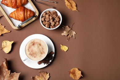 Photo of Flat lay composition with cup of hot drink on brown background, space for text. Cozy autumn atmosphere