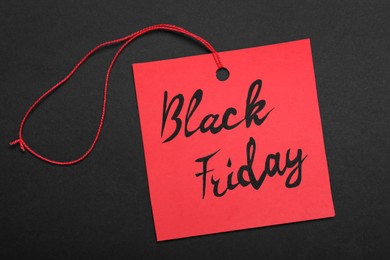 Photo of Black Friday red tag on color background, top view