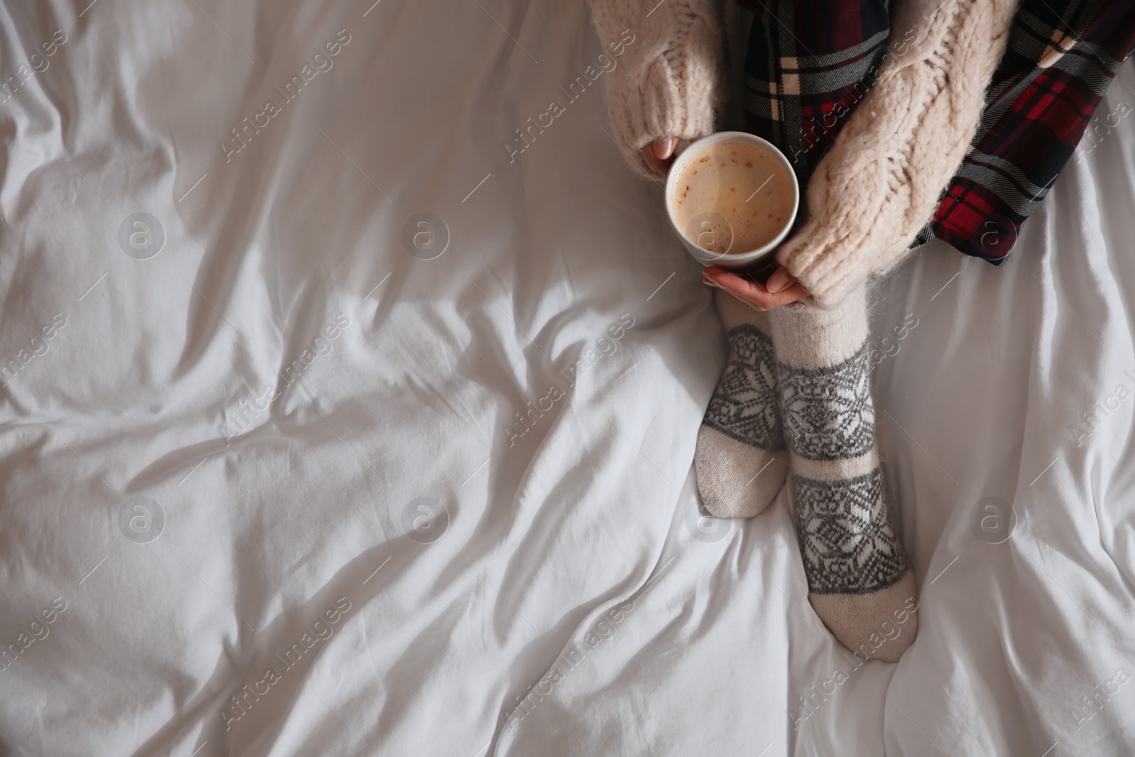 Photo of Woman with cup of coffee on soft blanket, top view. Space for text