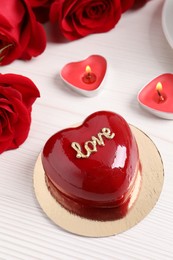 Photo of St. Valentine's Day. Delicious heart shaped cake, roses and candles on white wooden table