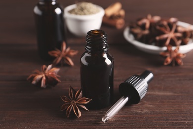 Photo of Anise essential oil and spice on wooden table