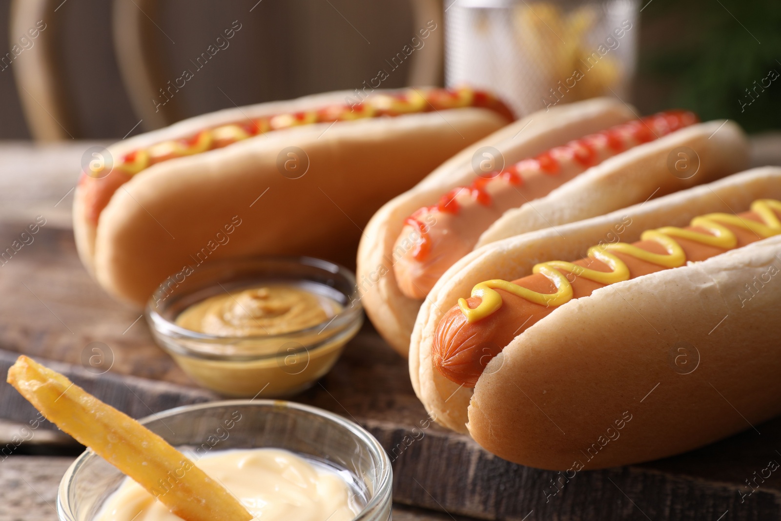 Photo of Delicious hot dogs with sauces and French fry on table, closeup