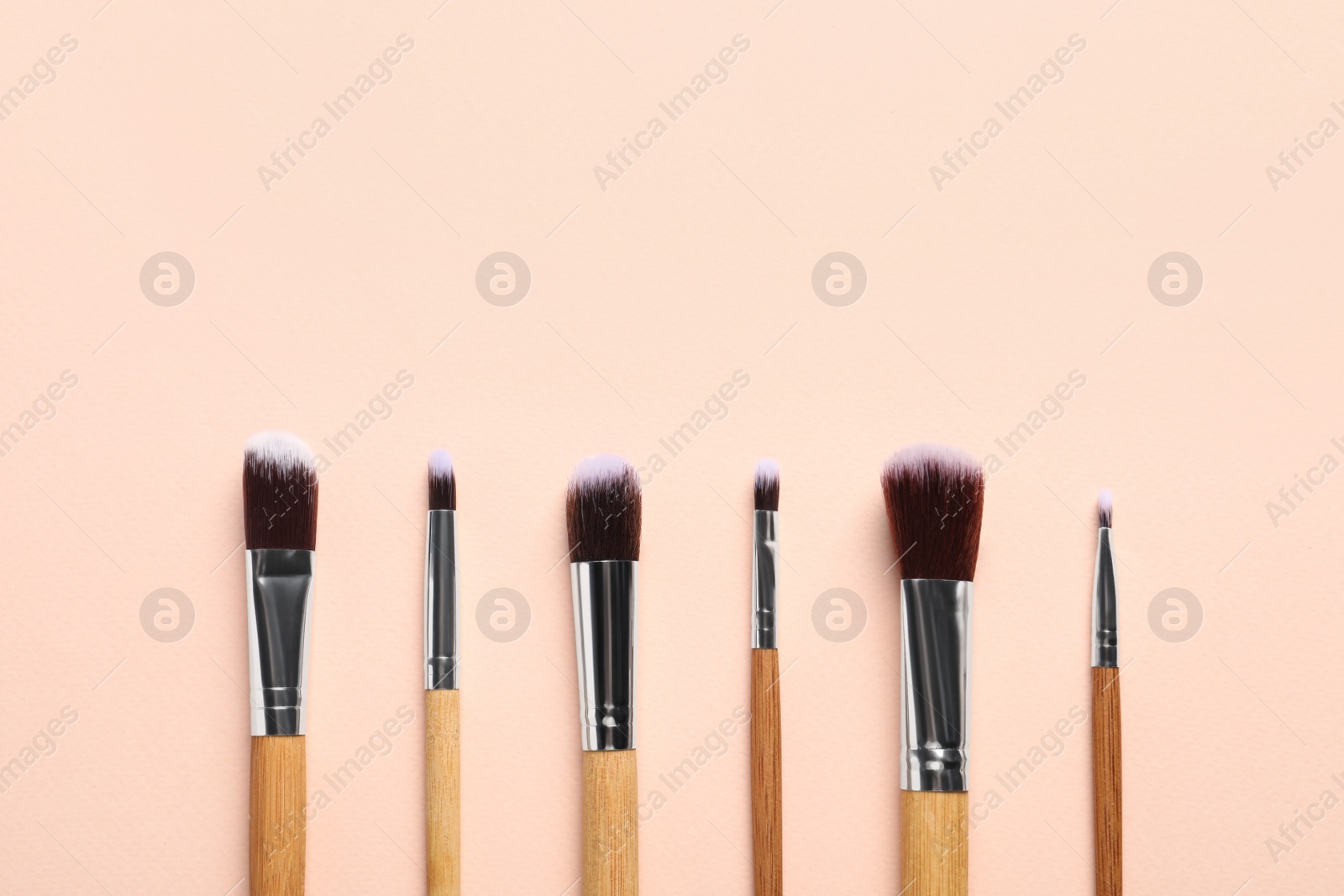 Photo of Set of makeup brushes on beige background, flat lay. Space for text