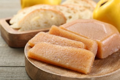 Photo of Tasty sweet quince paste, fresh fruits and bread on wooden table, closeup