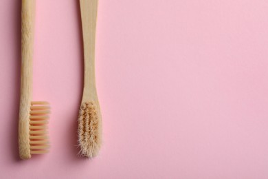 Photo of Two bamboo toothbrushes on pink background, flat lay. Space for text