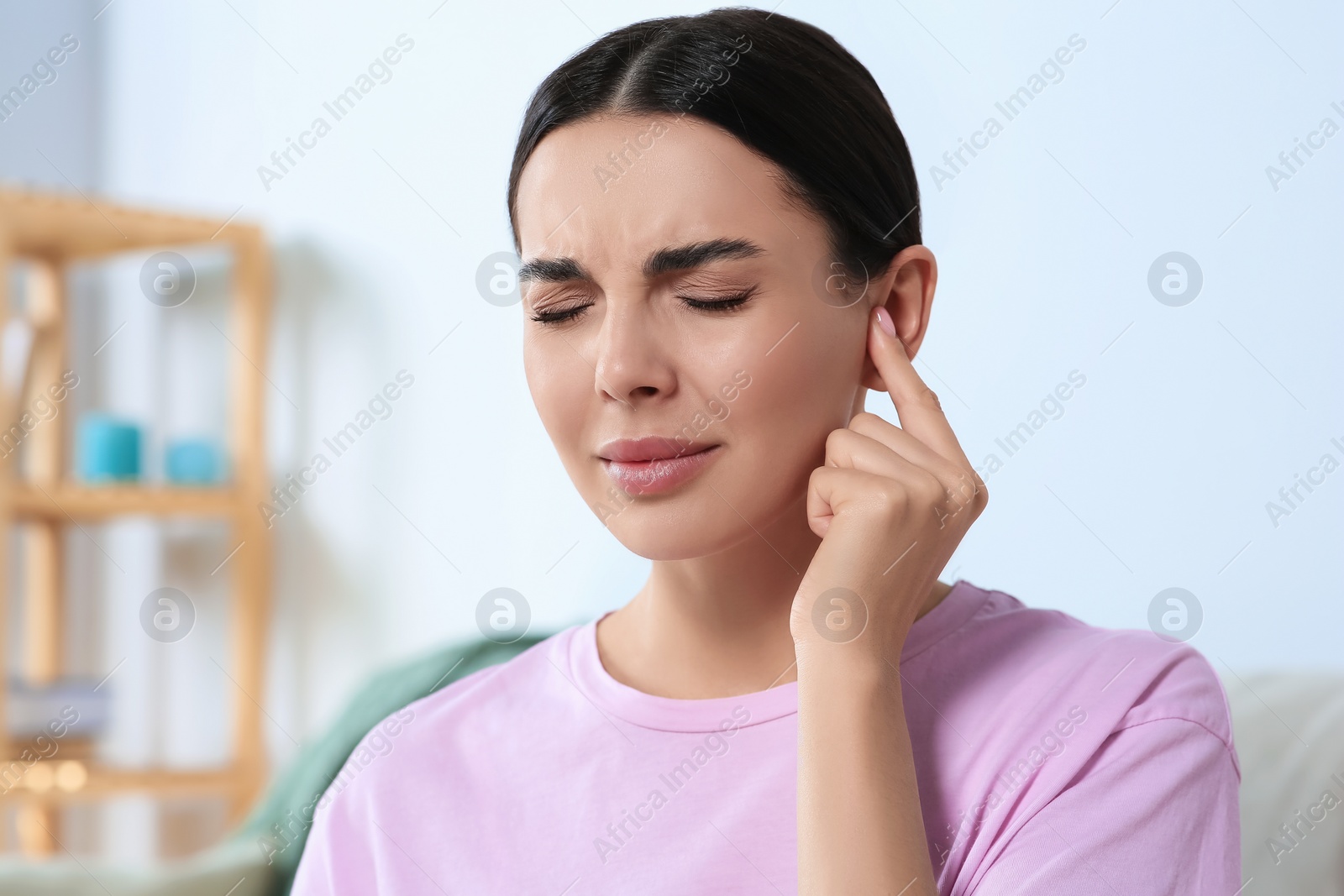 Photo of Young woman suffering from ear pain at home