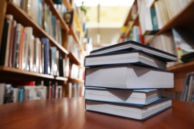 Photo of Stack of books on table in library. Space for text