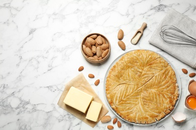 Traditional galette des rois and ingredients on white marble table, flat lay. Space for text