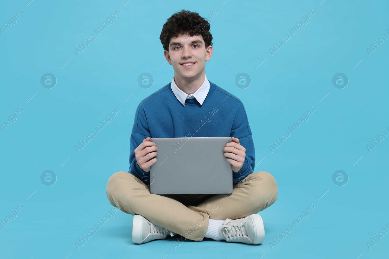 Photo of Portrait of student with laptop on light blue background