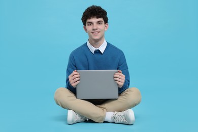 Portrait of student with laptop on light blue background