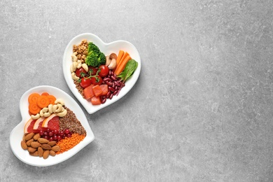 Photo of Plates with heart-healthy diet products on grey background, top view. Space for text