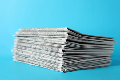 Photo of Stack of newspapers on light blue background. Journalist's work