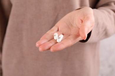 Photo of Woman holding antidepressants with sad and happy emoticons, closeup view