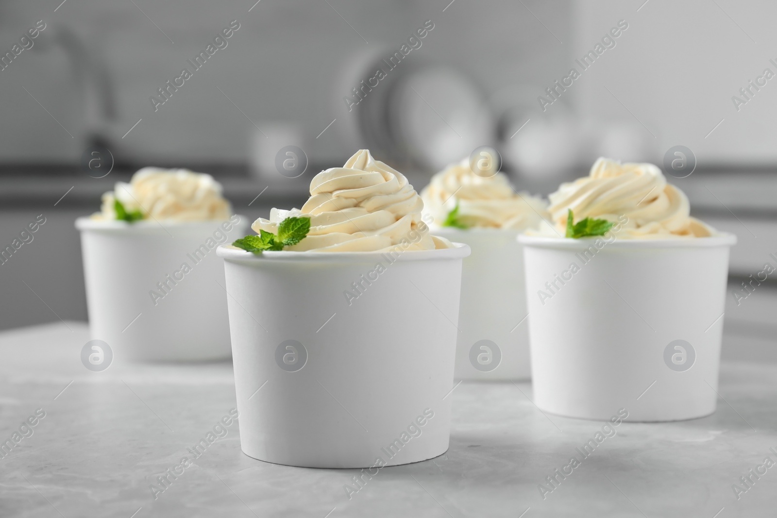 Photo of Cups with tasty frozen yogurt on grey table indoors