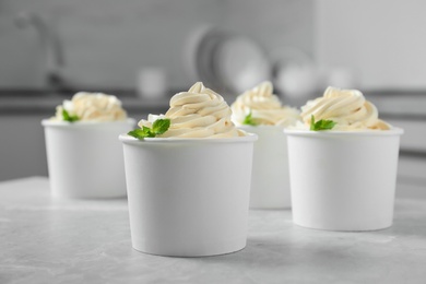 Cups with tasty frozen yogurt on grey table indoors