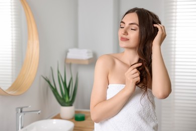 Photo of Young woman applying cosmetic hair mask in bathroom. Space for text