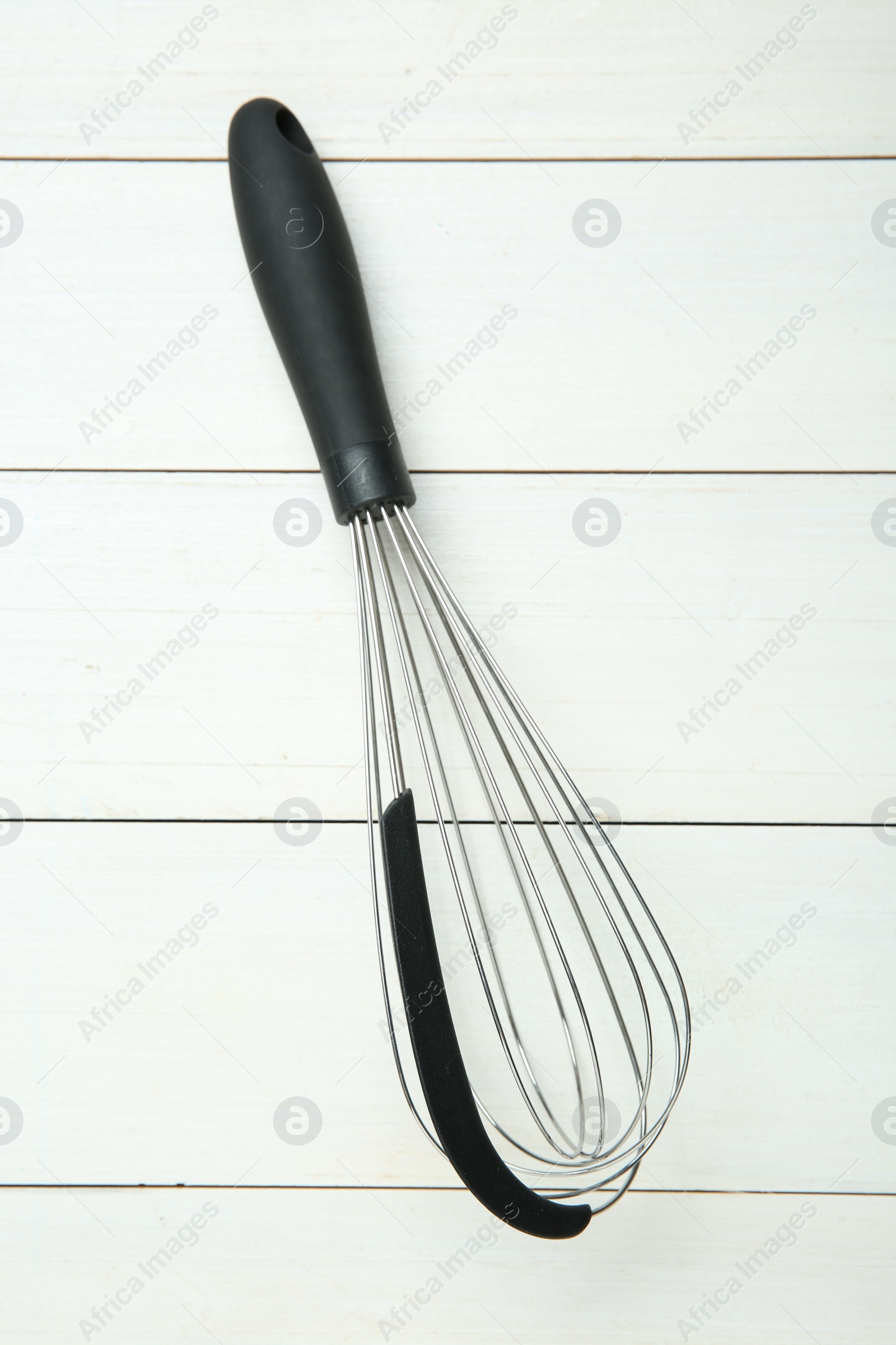 Photo of Metal whisk on white wooden table, top view