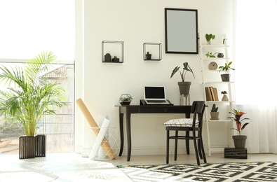 Photo of Trendy room interior with different home plants and laptop on table. Space for text