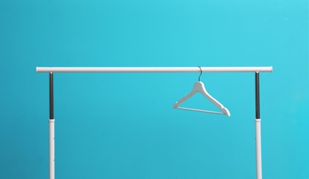 Photo of Wardrobe rack with hanger on color background