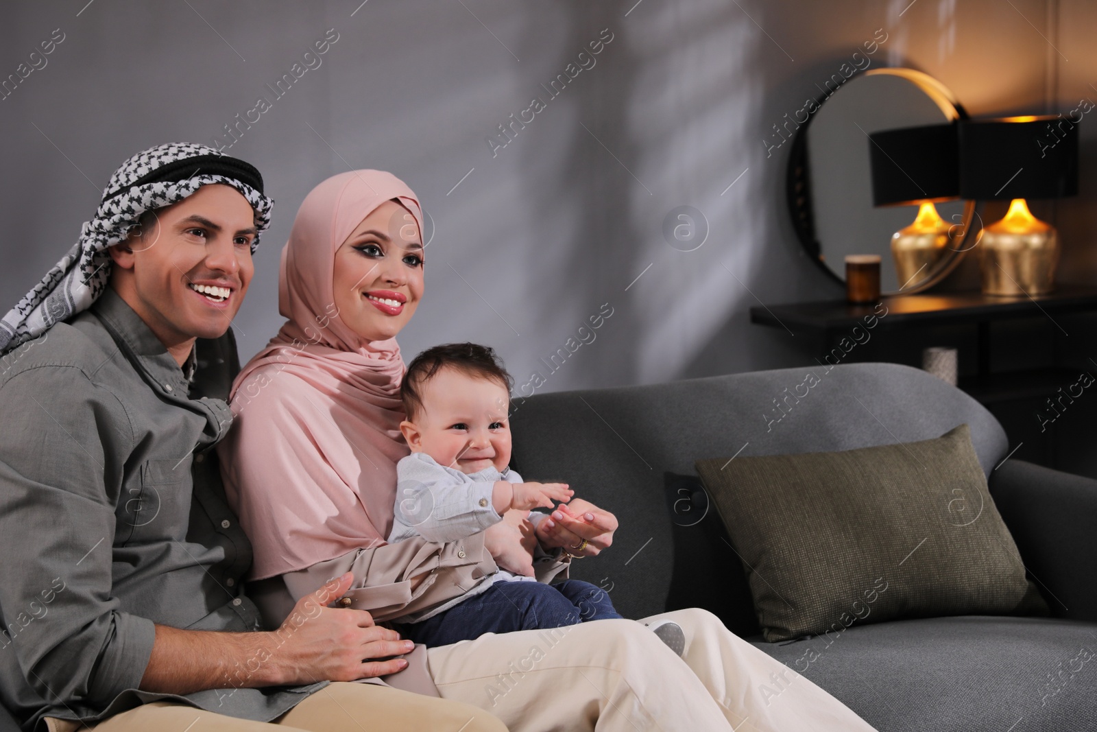 Photo of Happy Muslim family with little son in living room