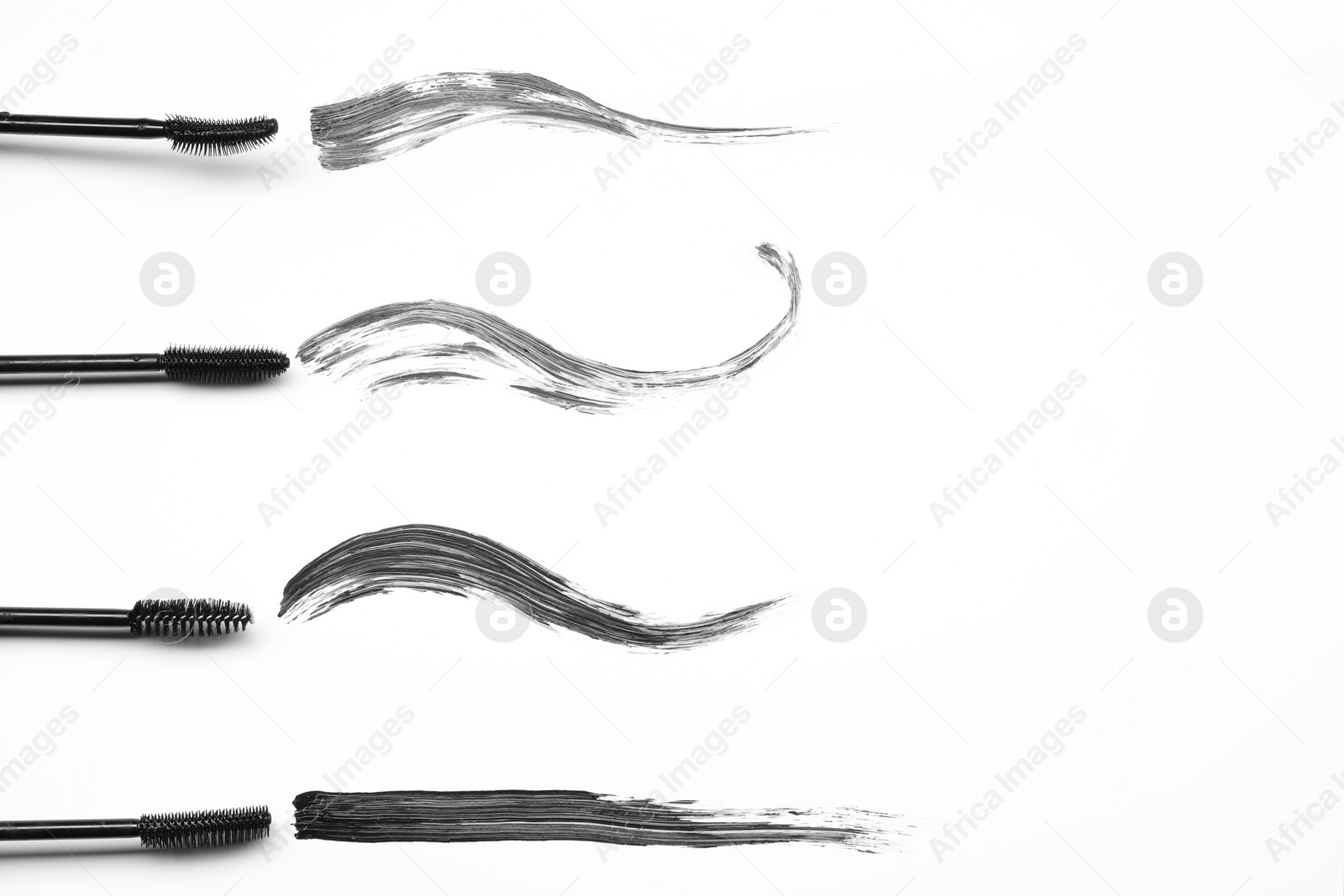 Photo of Smears of black mascara and applicators on white background, flat lay. Space for text