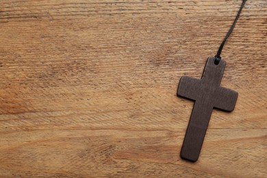 Photo of Christian cross on wooden table, top view. Space for text