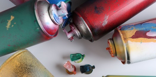 Many spray paint cans on white background, flat lay