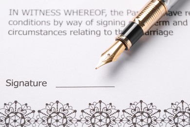 Photo of Marriage contract and pen on table, closeup