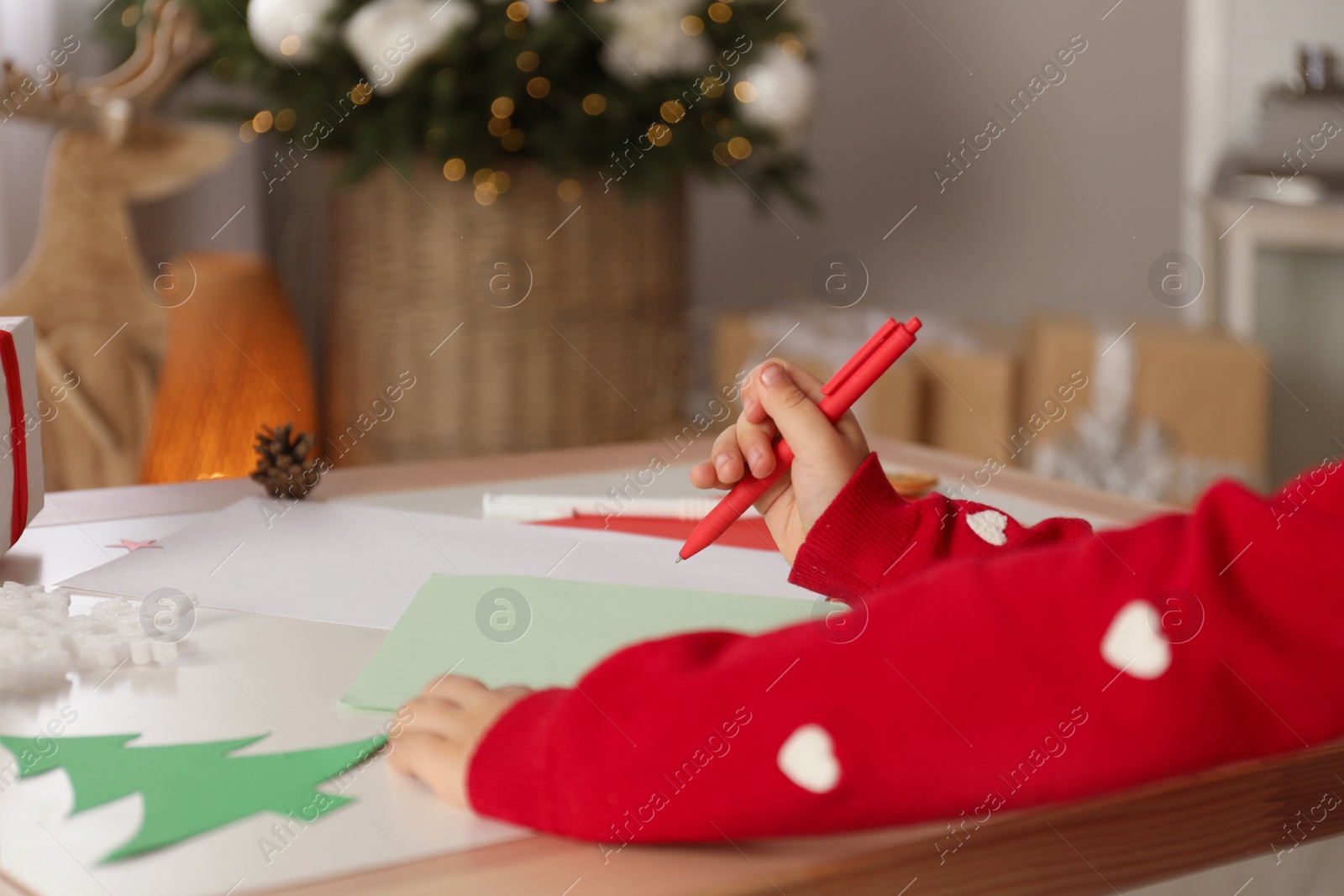 Photo of Cute child writing letter to Santa Claus at table, closeup. Christmas tradition