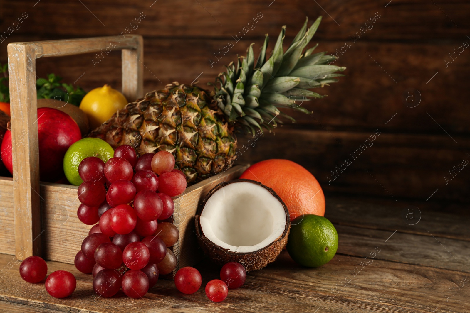 Photo of Crate and different ripe fruits on wooden table. Space for text