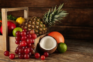 Crate and different ripe fruits on wooden table. Space for text