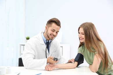 Doctor checking young woman's pulse in hospital