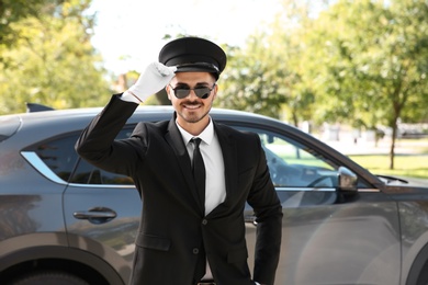 Photo of Young handsome driver standing near luxury car. Chauffeur service