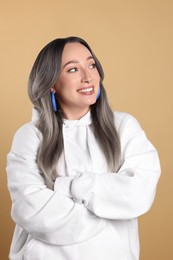 Smiling woman with ash hair color on beige background