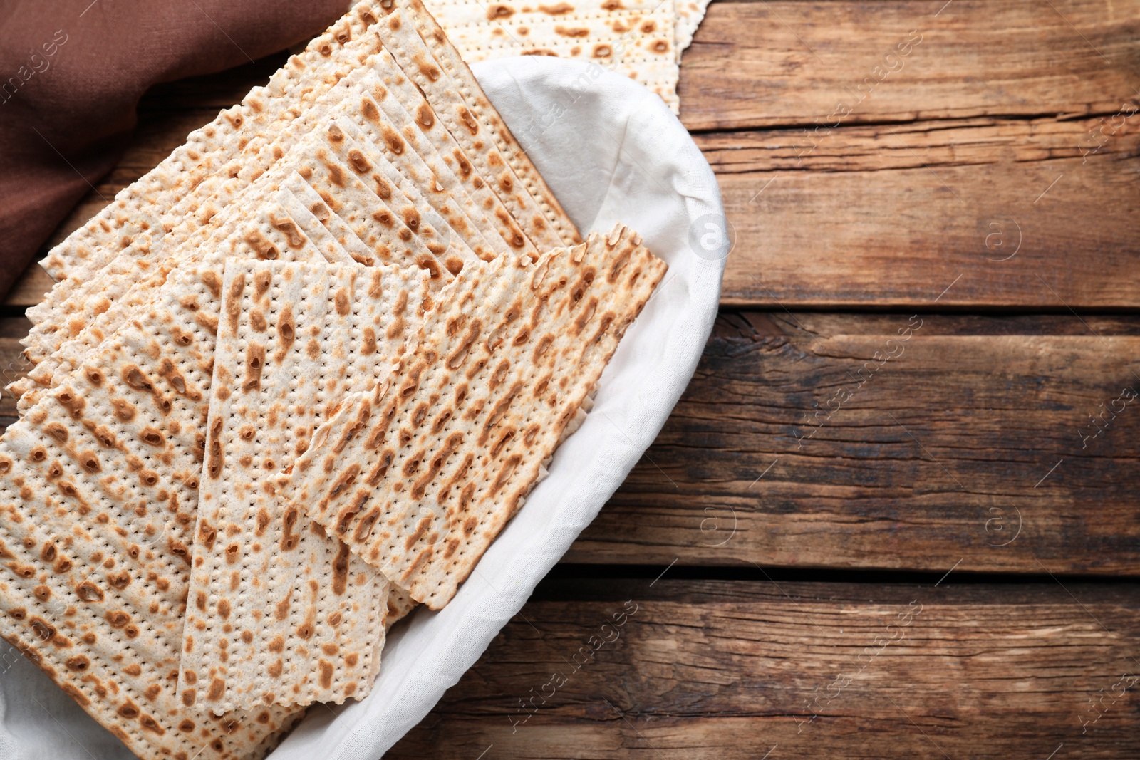 Photo of Traditional matzos in basket on wooden table, flat lay. Space for text