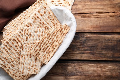 Photo of Traditional matzos in basket on wooden table, flat lay. Space for text