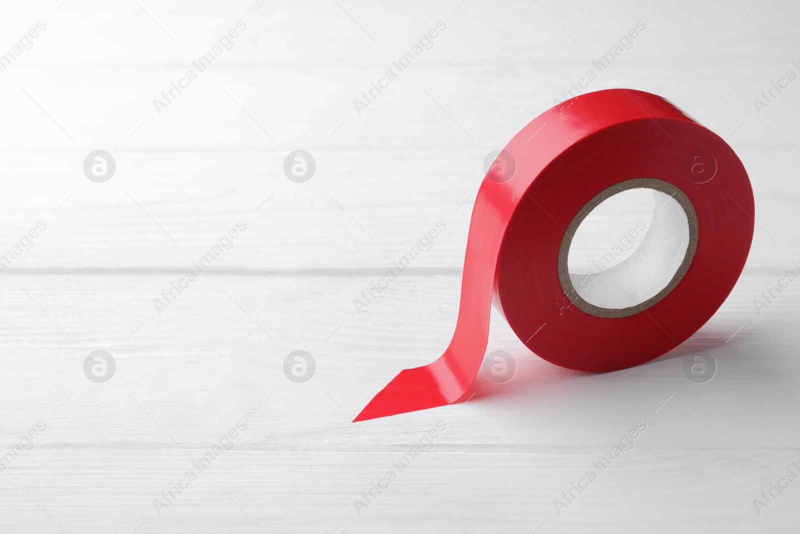 Photo of Red insulating tape on white wooden table, space for text