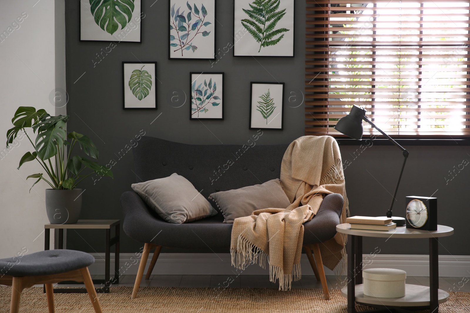 Photo of Beautiful artworks and comfortable sofa in stylish room. Interior design