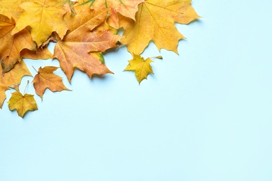 Photo of Pile of autumn leaves on blue background, top view. Space for text