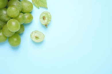 Photo of Ripe green grapes on light blue background, flat lay. Space for text