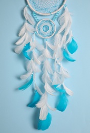 Photo of Beautiful dream catcher hanging on light blue background