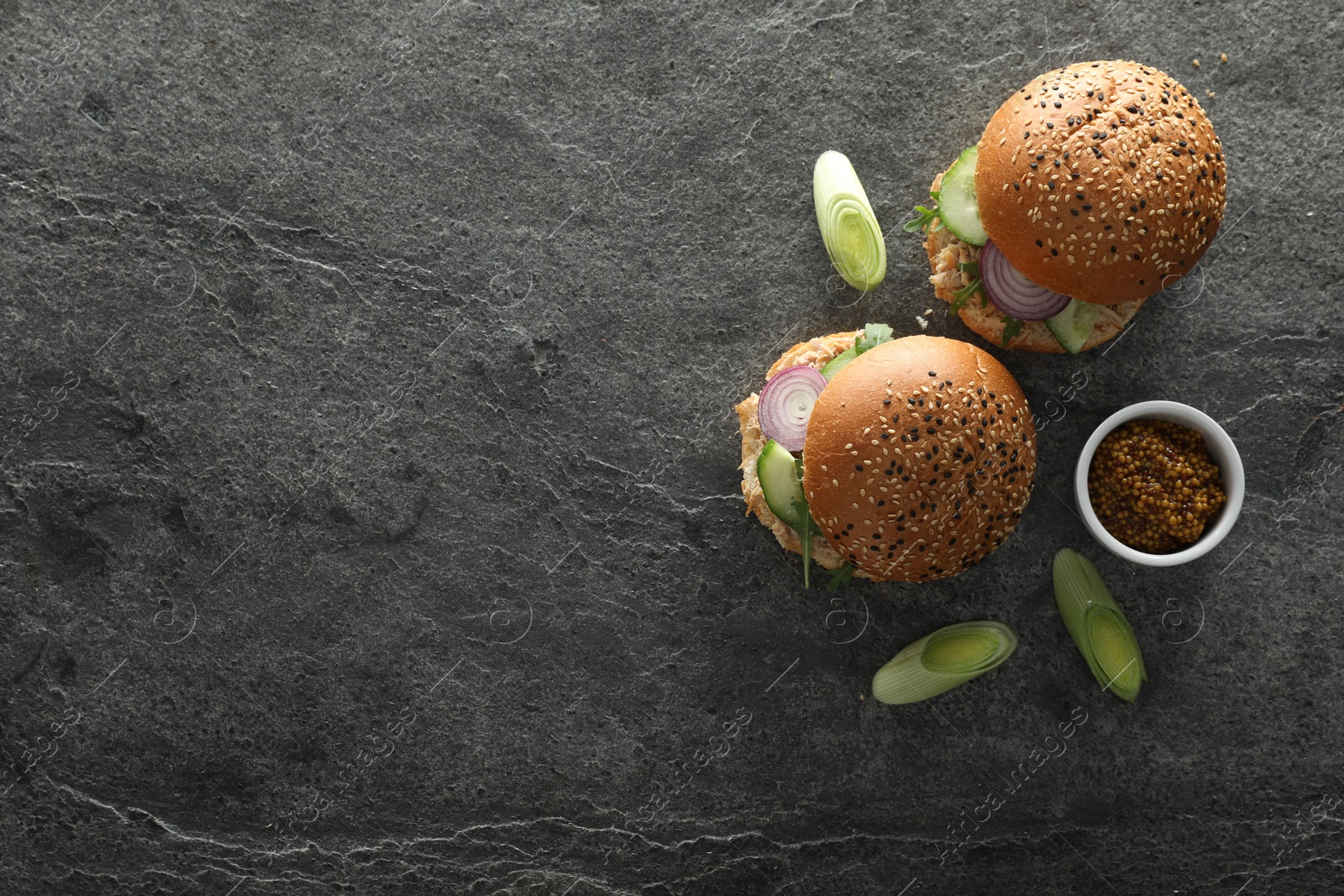 Photo of Food photography. Delicious burgers with onion and greens on gray textured table, flat lay with space for text