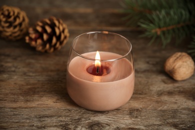 Burning candle in glass holder on wooden table