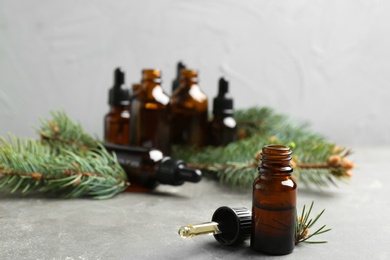 Composition with bottle of conifer essential oil on grey table. Space for text